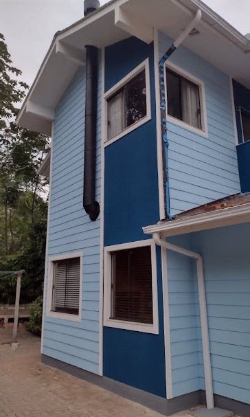 Casa de madeira pintada em azul-claro com faixa azul-marinho e acabamentos brancos