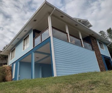 Casa de madeira de dois pisos pintada em azul-claro com base azul-marinho