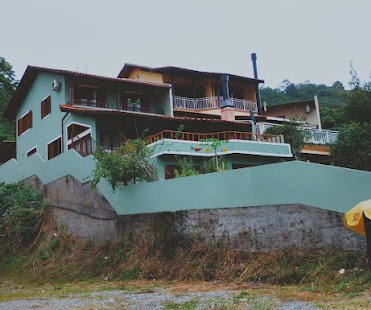 Casa em terreno inclinado com muro e fachada verde-água