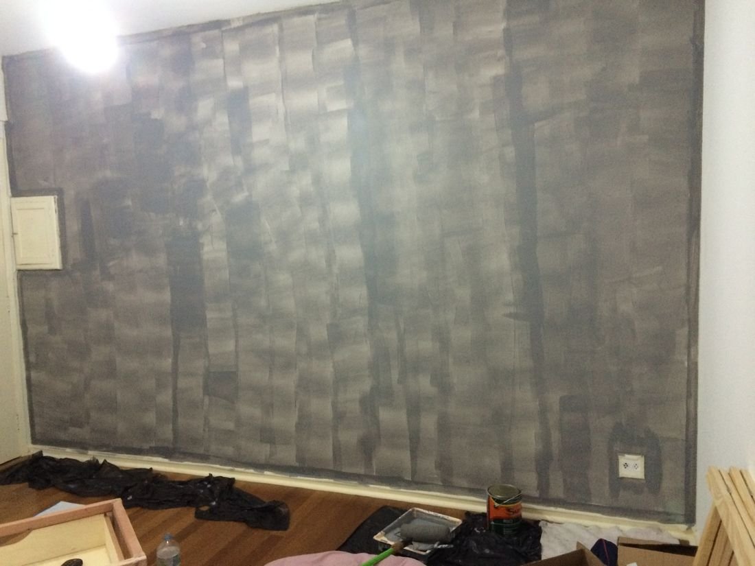 Parede pintada de cinza com manchas e marcas de rolo aparentes